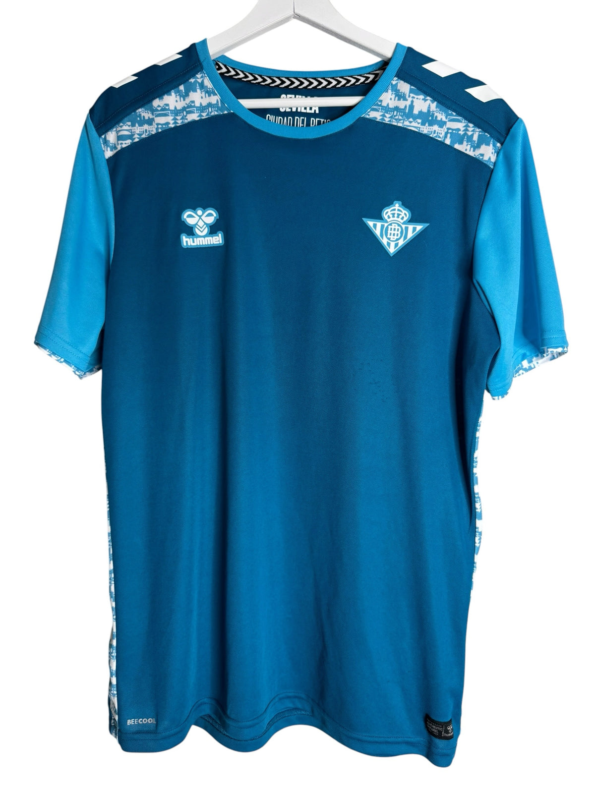 Maillot d'entraînement Hummel Real Betis bleu avec technologie BeeCool, détails graphiques et blason du club.